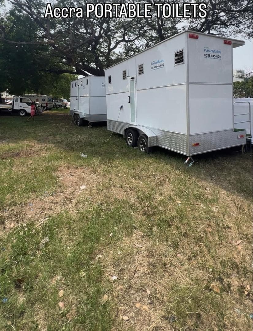 Several restroom trailers positioned on grass at an outdoor venue