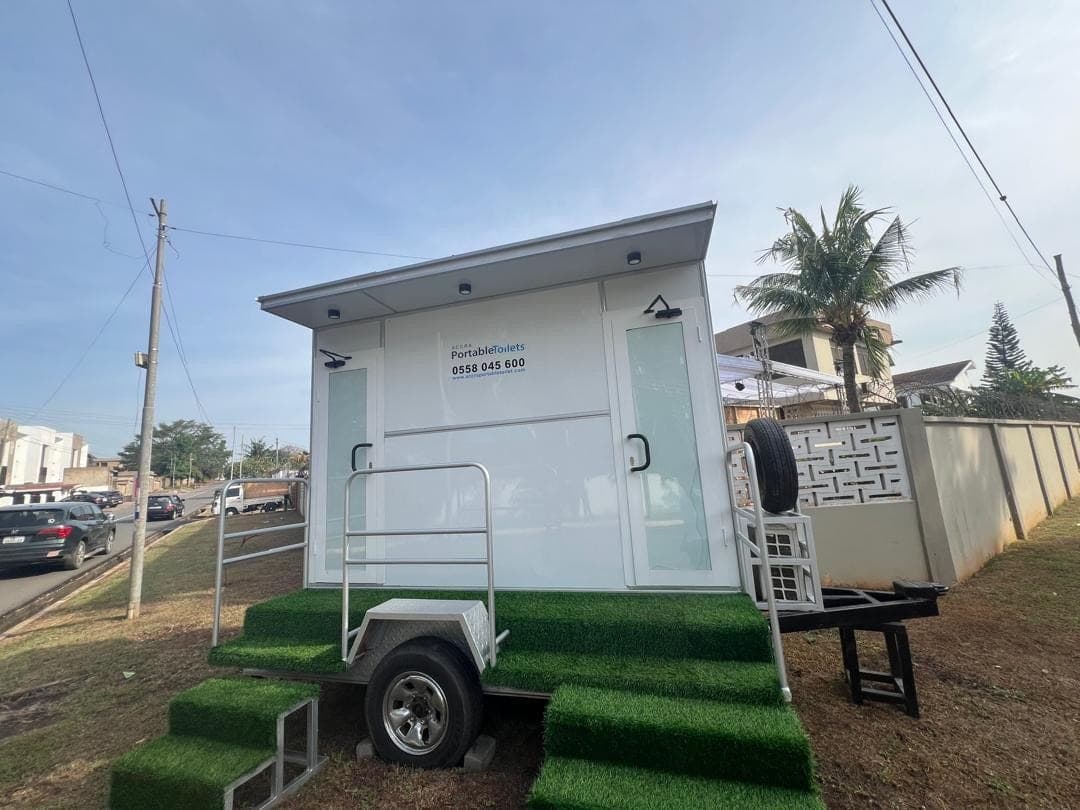 Two-door restroom trailer set down at the roadside on turf steps
