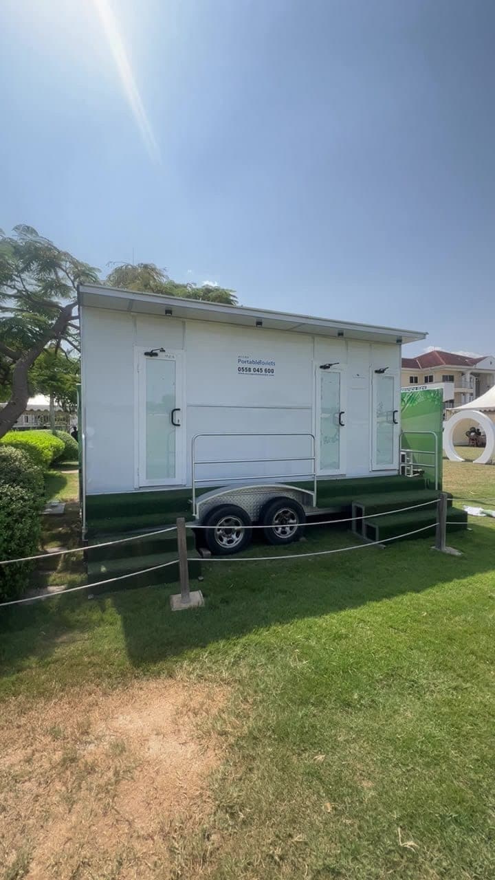 Executive 3-door restroom trailer set up on a lawn at an outdoor event