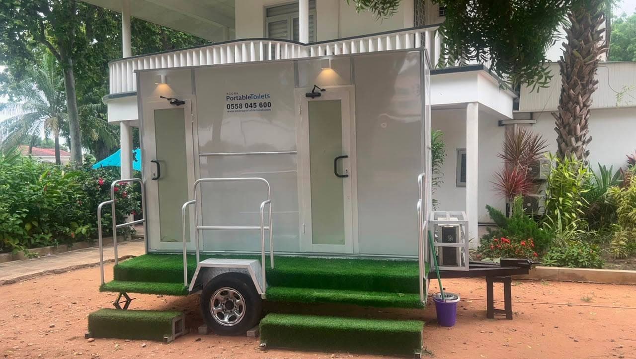 2-door restroom trailer at a garden event with the door lights on