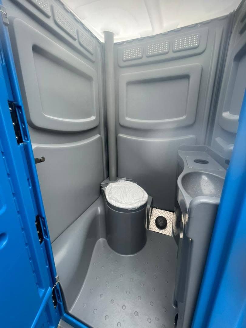 Inside a standard cubicle — flushing WC, corner wash basin and foot pump
